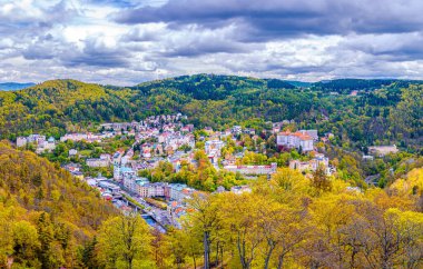 Karlovy Vary şehrinin havadan panoramik manzarası. Tarihi şehir merkezinde renkli binalar ve spa otelleri var. Sonbaharda Karlsbad kasabası ve Slavkov Ormanı dağlarının manzarası