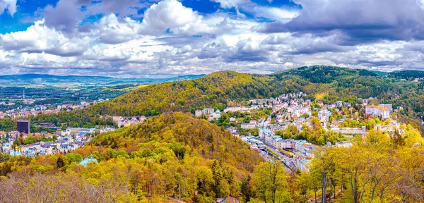 Karlovy Vary şehrinin havadan panoramik manzarası. Tarihi şehir merkezinde renkli binalar ve spa otelleri var. Sonbaharda Karlsbad kasabası ve Slavkov Ormanı tepelerinin manzarası