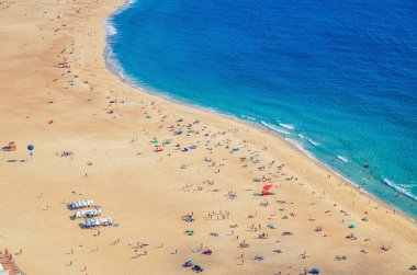 Turistlerin güneşlendiği ve Atlantik Okyanusu 'nun mavi suları, Praia da Nazare kasabasının dalgalı kıyı şeridi, Leiria Bölgesi, Oeste Bölgesi, Portekiz