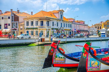 Aveiro, Portekiz, 13 Haziran 2017: Geleneksel renkli Moliceiro teknesi Aveiro şehrinin tarihi merkezinde su kanalında demirliyor, güneşli bir yaz günü, tipik binalar ve mavi gökyüzü arka planı
