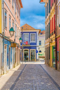 Aveiro, Portekiz, 13 Haziran 2017: Aveiro şehrinin parke taşı caddesinde güneşli yaz gününde mavi gökyüzü arka planında tipik renkli azulejos döşeli evler