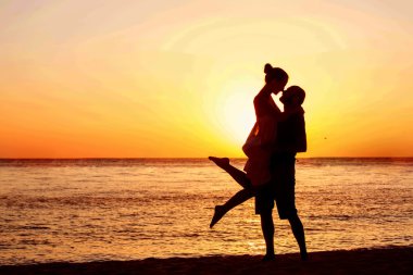 Romantic couple on the beach at colorful sunset on background clipart