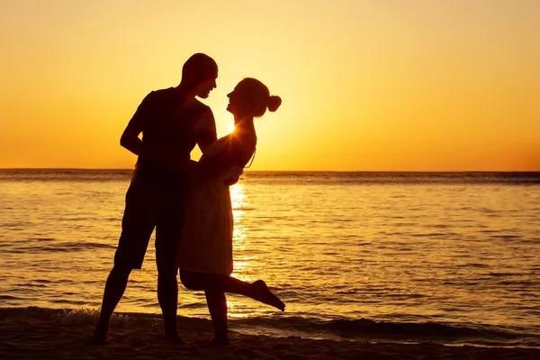 背景にカラフルな夕日でビーチでロマンチックなカップル — ストック写真