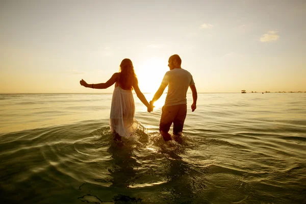 Pareja romántica en la playa al atardecer colorido en el fondo — Foto de Stock