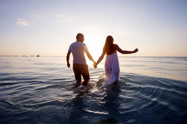 背景にカラフルな夕日でビーチでロマンチックなカップル — ストック写真