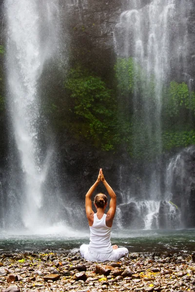 Woman meditating doing yoga between waterfalls — Stock Photo, Image