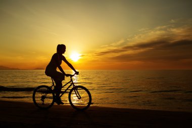  Plajda bisiklet süren bir kadın.