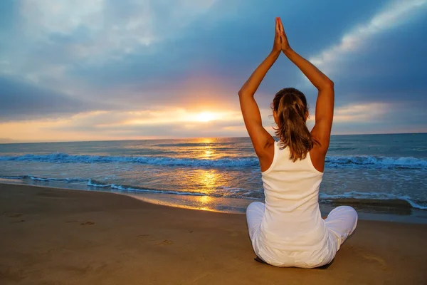 Kaukasisk kvinna utövar yoga på stranden — Stockfoto