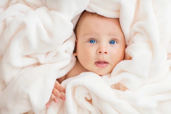 Caucasian baby boy covered with  towel joyfully smiles at camera — Stock Photo, Image