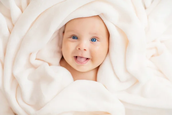 Caucasian baby boy covered with  towel joyfully smiles at camera — Stock Photo, Image