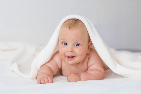 Erkek beyaz bebek havlu ile kaplı sevinçle gülümsüyor kameraya — Stok fotoğraf
