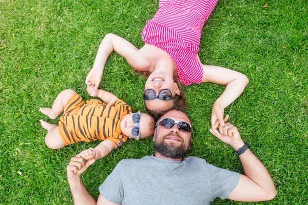 La famille s'amuse à l'herbe verte près de la piscine pendant la journée d'été — Photo