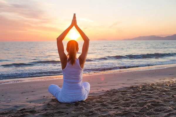 Kaukasisk kvinna utövar yoga på stranden — Stockfoto