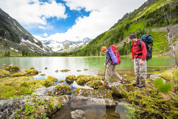 Pár je turistika na stezce u jezera v pohoří Altaj — Stock fotografie