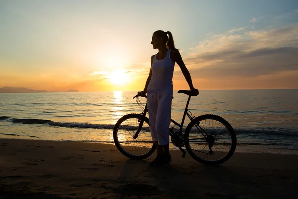 Frau im Urlaub radelt am Strand — Stockfoto