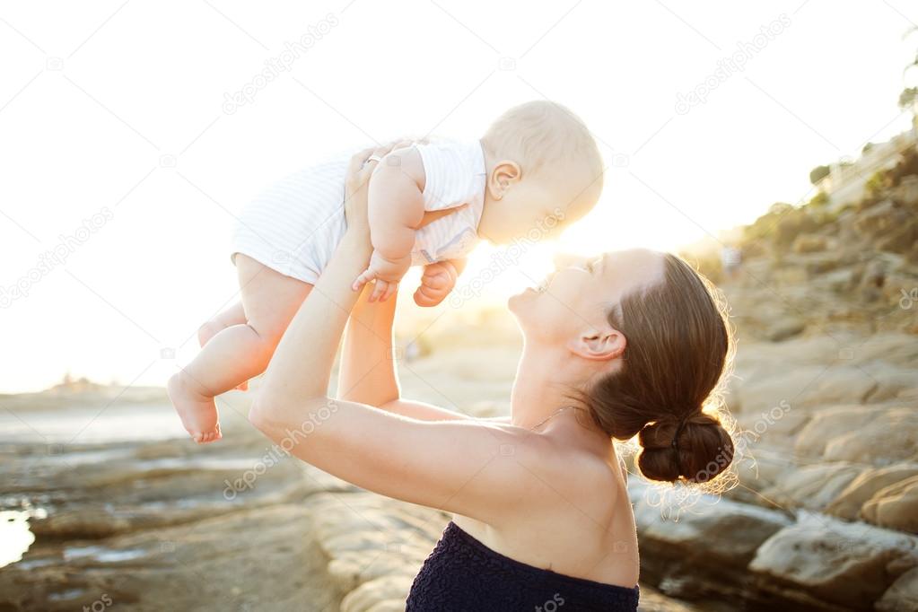 Mother and her son have great time at the seashore at sunset