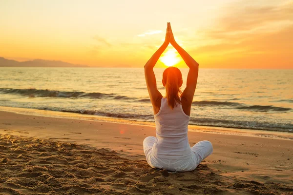 Mujer caucásica practicando yoga en la orilla del mar — Foto de Stock