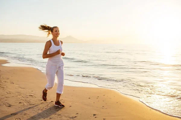 Kaukasisk kvinna jogging på havsstranden — Stockfoto