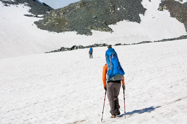 Mochileros están pasando campo de nieve en la montaña rocosa en Altai mo — Foto de Stock