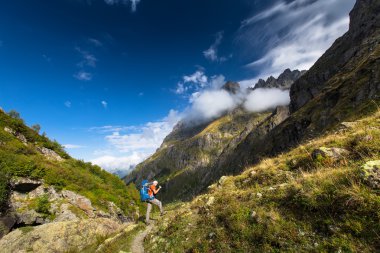 Georgia 'daki Kafkasya dağlarında sırt çantalı bir adam yürüyüş yapıyor.