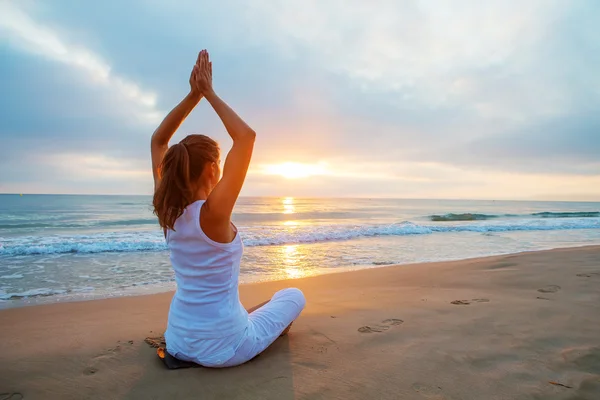 Kaukasische vrouw beoefenen van yoga in kust — Stockfoto
