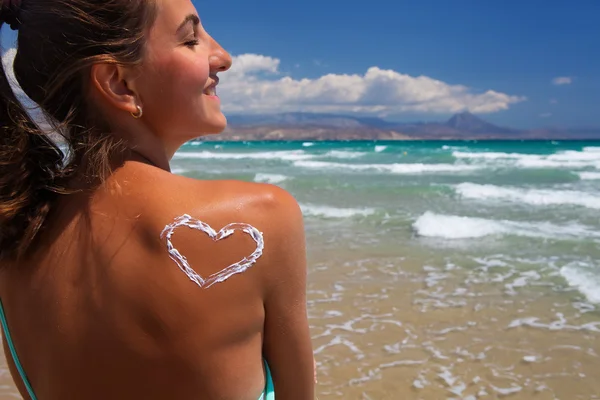 Een hart van de crème op de vrouwelijke rug op het strand — Stockfoto