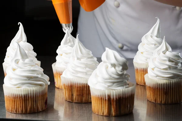 Decorating cupcakes with white cream — Stock Photo, Image