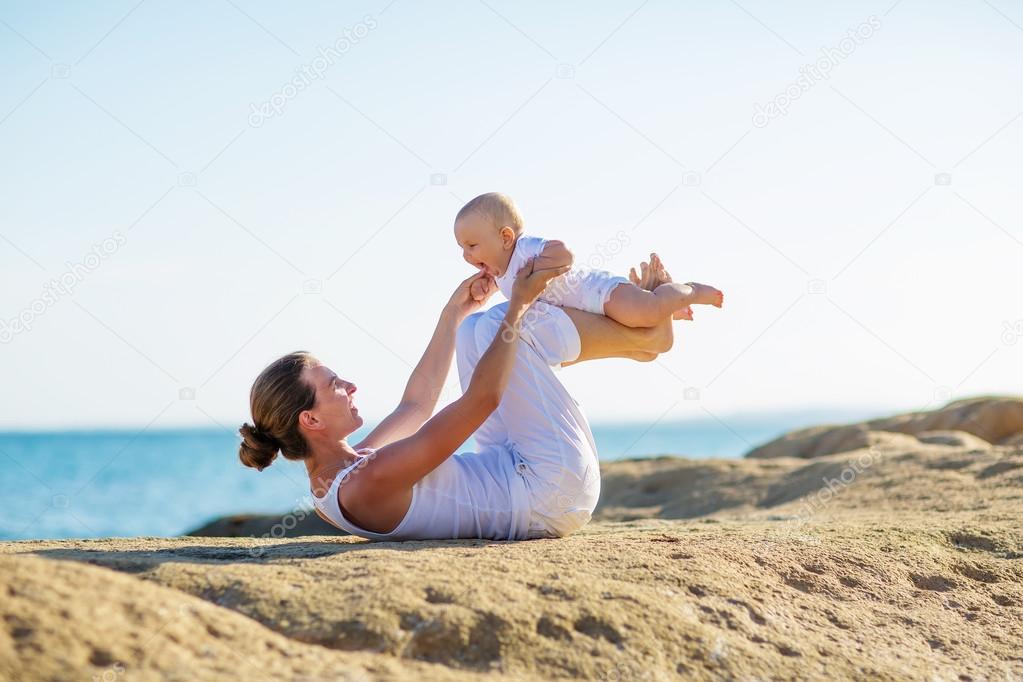 mother and son doing exercises on beach. 