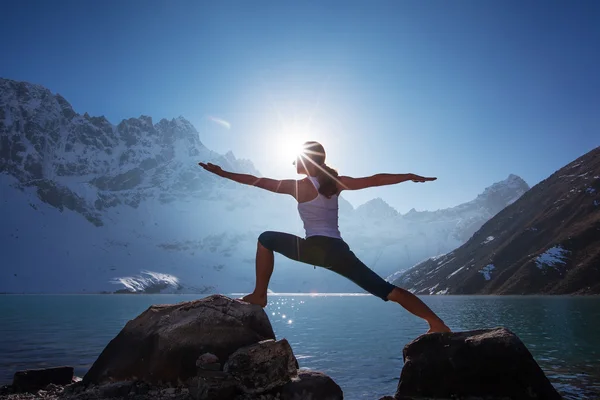 Mujer joven está practicando yoga en el lago de montaña — Foto de Stock