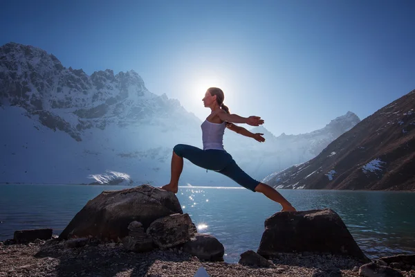 Young woman is practicing yoga at mountain lake — Stock Photo, Image