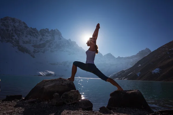 Mujer joven está practicando yoga en el lago de montaña — Foto de Stock