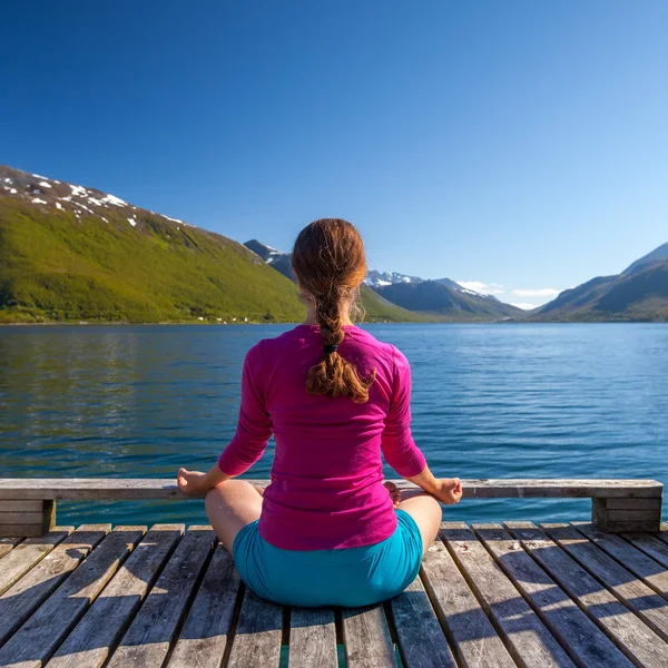 Kaukasisk kvinna gör yoga övningar mot pittoreska lan — Stockfoto