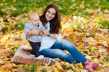 Örme kazak pumpki arasında annesiyle oynayan erkek bebek