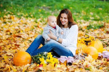 Örme kazak pumpki arasında annesiyle oynayan erkek bebek