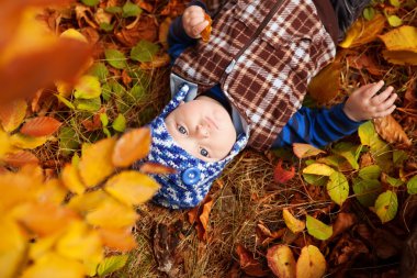 Örme kazaklı çocuk sonbahar Park'ta oturuyor