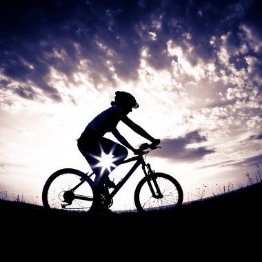 Gün batımında çayırda bisikletli kız.