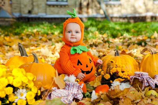 Niño en traje de calabaza sobre fondo de hojas de otoño — Foto de Stock