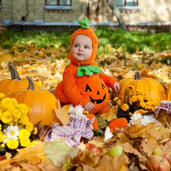 Niño en traje de calabaza sobre fondo de hojas de otoño — Foto de Stock