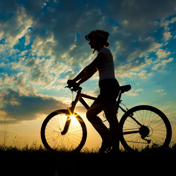 Biker-girl at the sunset on the meadow — Stock Photo, Image