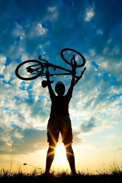 Biker hält Fahrrad hoch in den Himmel — Stockfoto