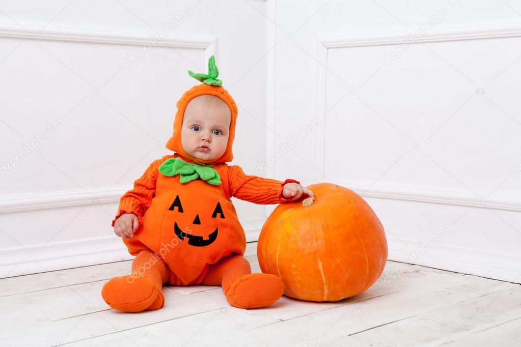 Child in pumpkin suit on white background with pumpkin 