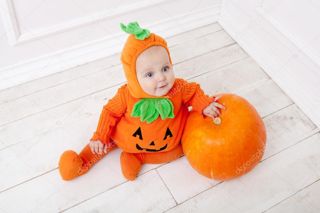 Child in pumpkin suit on white background with pumpkin 