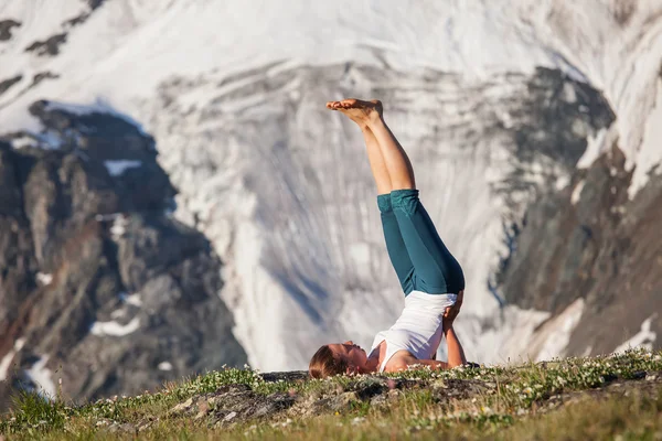 Mujer joven está practicando yoga en las altas montañas — Foto de Stock