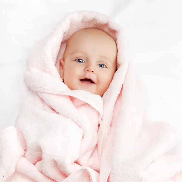 Caucasian baby boy covered with pink towel joyfully smiles at ca — Stock Photo, Image