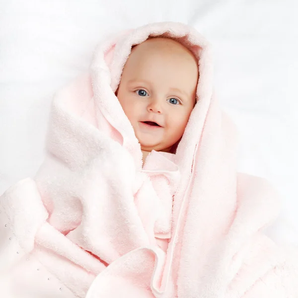 Caucasian baby boy covered with pink towel joyfully smiles at ca — Stock Photo, Image