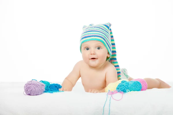 Kaukasiska söt pojke i roliga färgglada hatt mellan bollar av garn — Stockfoto