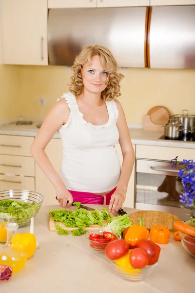 Mulher grávida prepara salada de legumes em casa — Fotografia de Stock