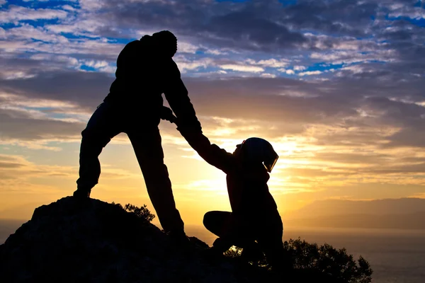 Silueta de pareja en la cima de la montaña en el mar mientras —  Fotos de Stock