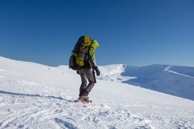 Backpacker kadın kış dağlarda güneşli günde yürüyor