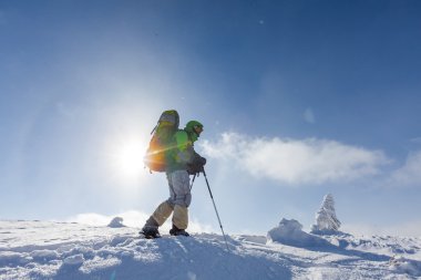 Kış dağlarda güneşli günde yürüyen backpacker adam